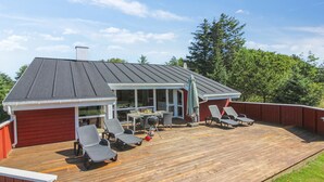 Una terraza cubierta con mobiliario exterior y una parrilla.