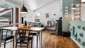 Una cocina moderna con suelo de madera, una zona de comedor con sillas negras y un amplio ventanal que ofrece vistas al exterior.