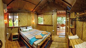 A bamboo-themed room with a bed, a small stool, and a bench. - Camotes hidden huts-rooms-bar-restaurant (San Francisco)