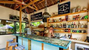 A bar area with a wooden counter, stools, and shelves stocked with bottles. A sign above the counter reads "Pacific Soul Spirit 21." - Camotes hidden huts-rooms-bar-restaurant (San Francisco)