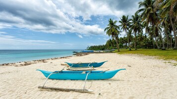 Una playa cerca, arena blanca, camas de playa gratis, sombrillas