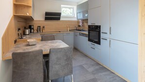 Eine moderne Küche mit grauen Schränken, einer Holz Arbeitsplatte und einem Essbereich mit grauen Stühlen.
