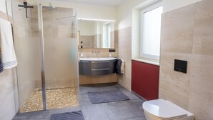 Ein modernes Badezimmer mit einer Duschkabine, einem Waschbecken mit Spiegel und einer Toilette.