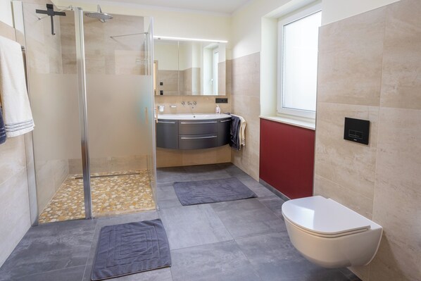 Un baño moderno con ducha acristalada, lavamanos con espejo y retrete.