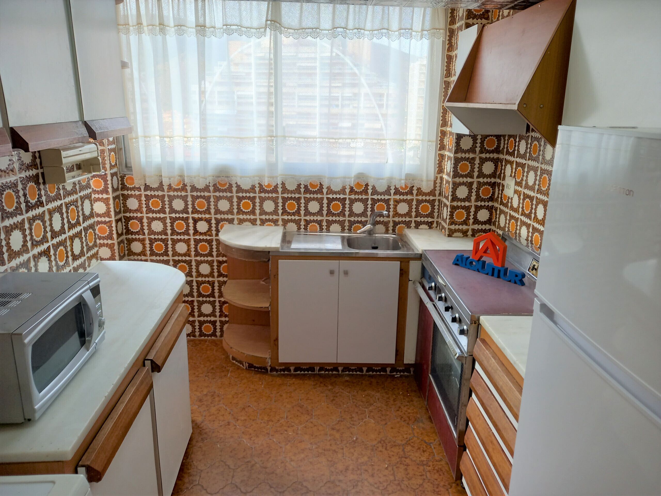 A compact kitchen with a sink, stove, and microwave.