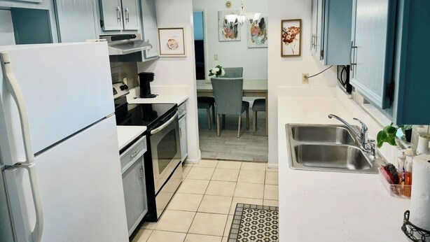 A compact kitchen with white appliances, a dining area, and a sink. - Elegant 3 Bedrooms with private pool, close to Disney World,Downtown Kissimmee. (Kissimmee)