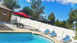 A swimming pool with blue water, surrounded by a white fence, and a red umbrella. - Elegant 3 Bedrooms with private pool, close to Disney World,Downtown Kissimmee. (Kissimmee)