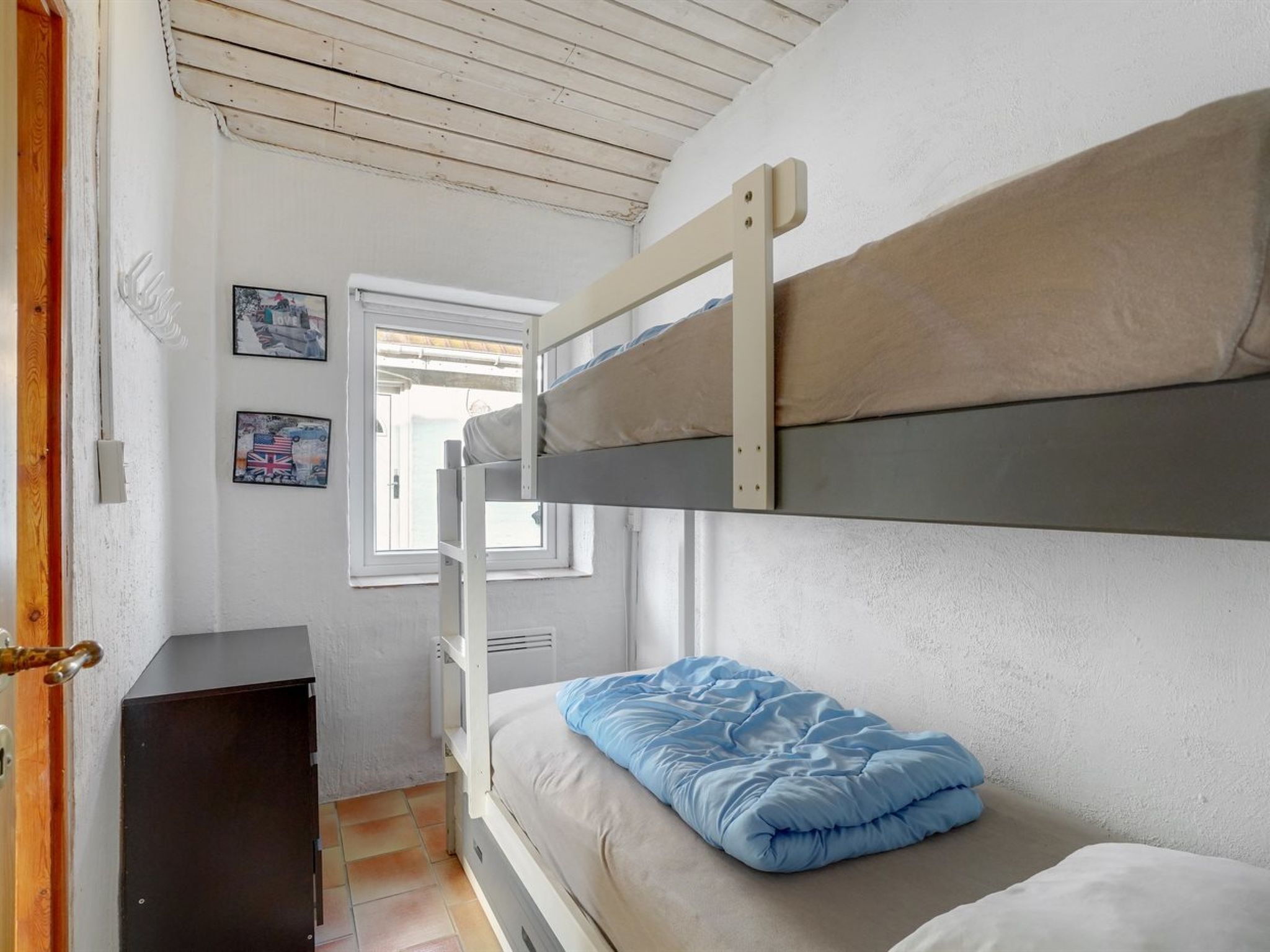 A bunk bed room with a window, a small desk, and wall decorations.