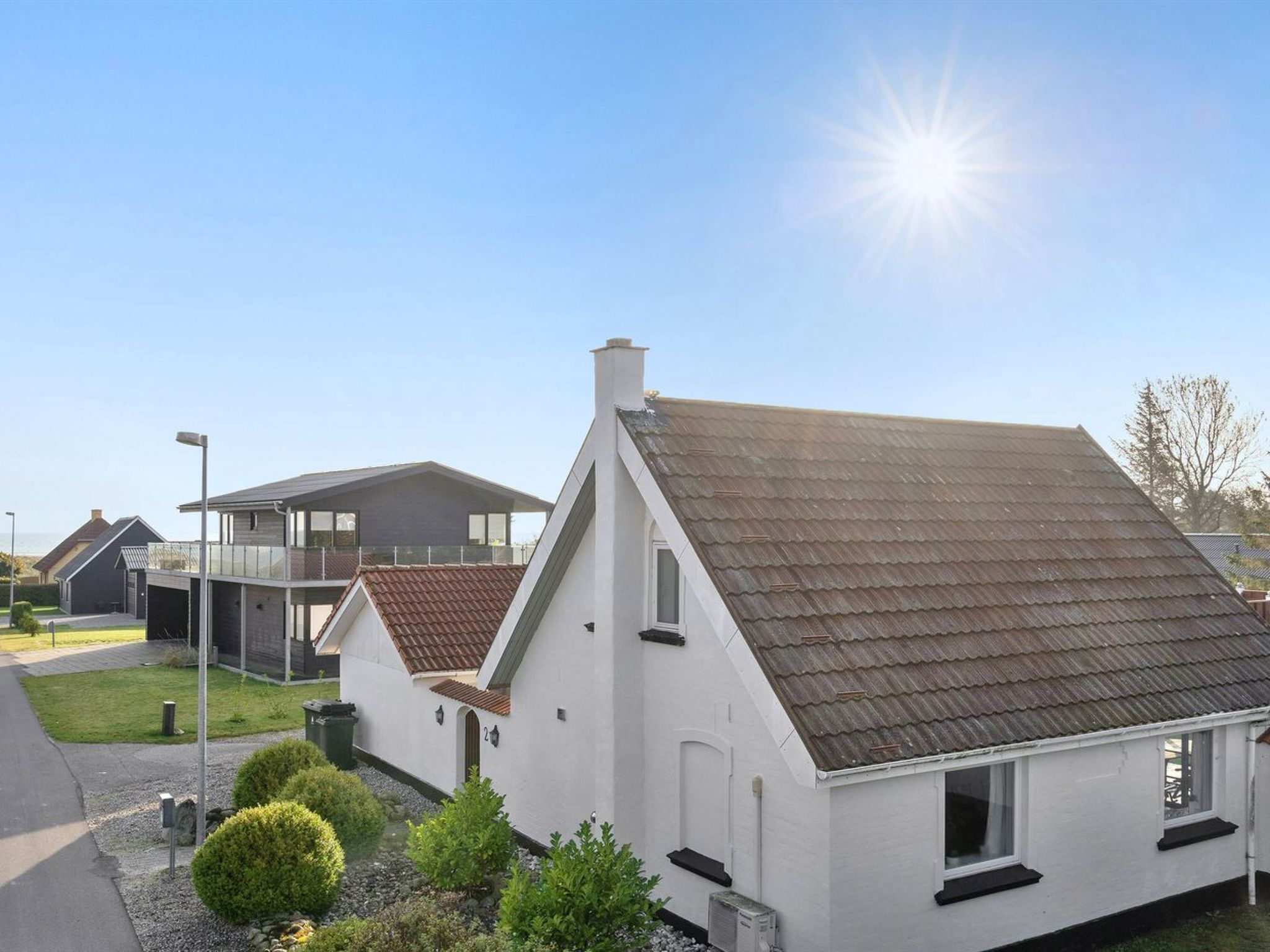Een moderne woonwijk met huizen met puntdaken en een heldere lucht.