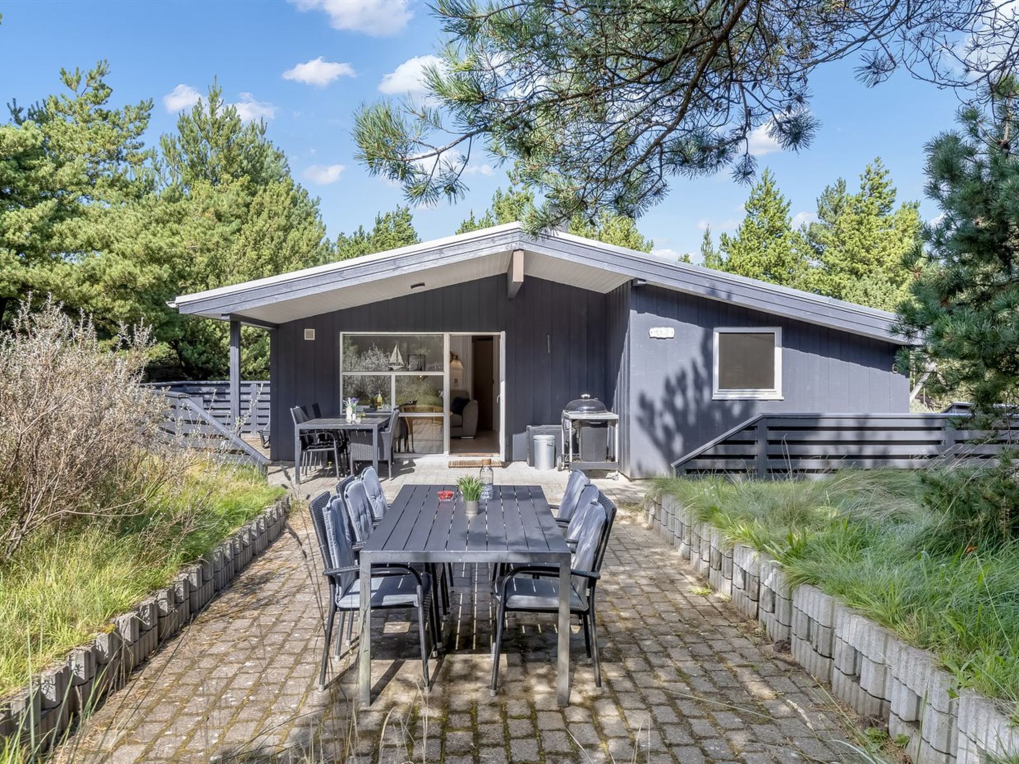 Uma casa moderna com um espaço de pátio, incluindo uma mesa, cadeiras, área coberta para sentar e uma grande janela.