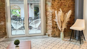 A room with a large glass door leading to an outdoor area, a small potted plant, a white chair, and pampas grass in a vase. - Apartamento en el Corazón de Casco Viejo Panamá 14 (Panamá)