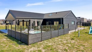 Une maison moderne dotée d’un patio entièrement vitré, d’une piscine et d’un toboggan.