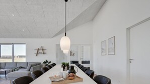 Un espace repas moderne avec une longue table dressée pour un repas, entourée de chaises.