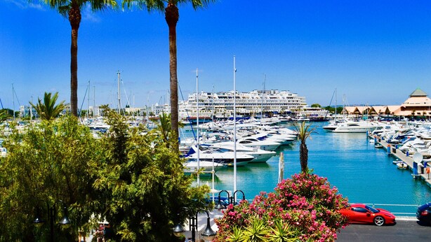 A marina with numerous boats docked, palm trees, and a red sports car parked in the foreground. - T1 TENIS GOLFMAR - PISCINA- WIFI- VILAMOURA (Vilamoura)