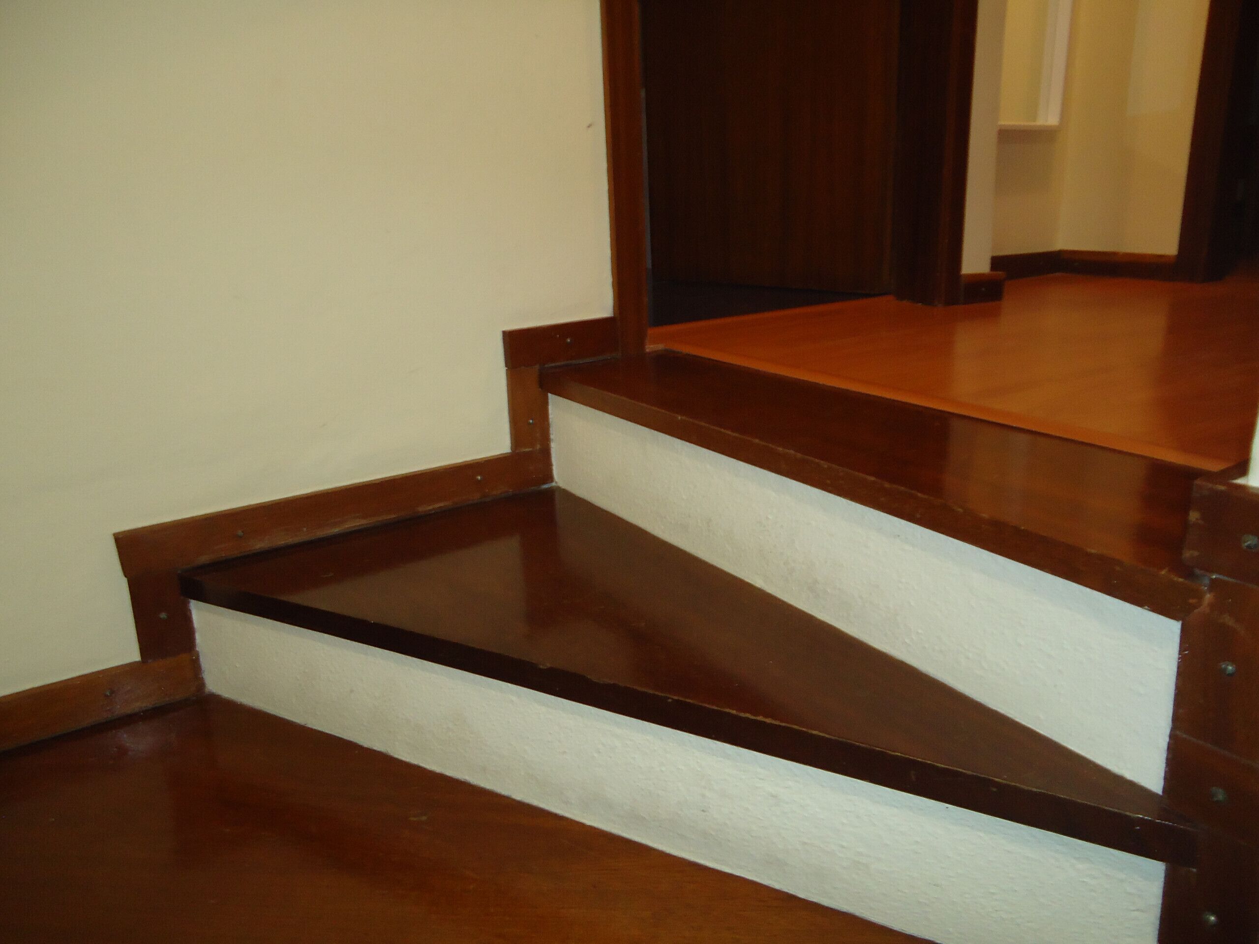 Una escalera de madera con peldaños de color oscuro y rellanos blancos.