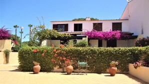 A building with a tiled patio, potted plants, and a hedge.