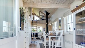 A spacious kitchen with wooden floors, white cabinetry, and a dining area with white chairs.