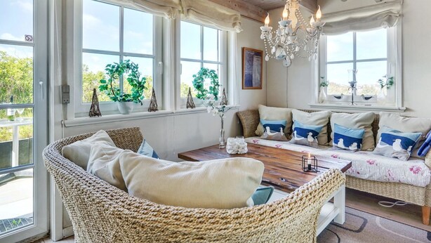 A cozy room with a wicker sofa, a wooden coffee table, and a chandelier.