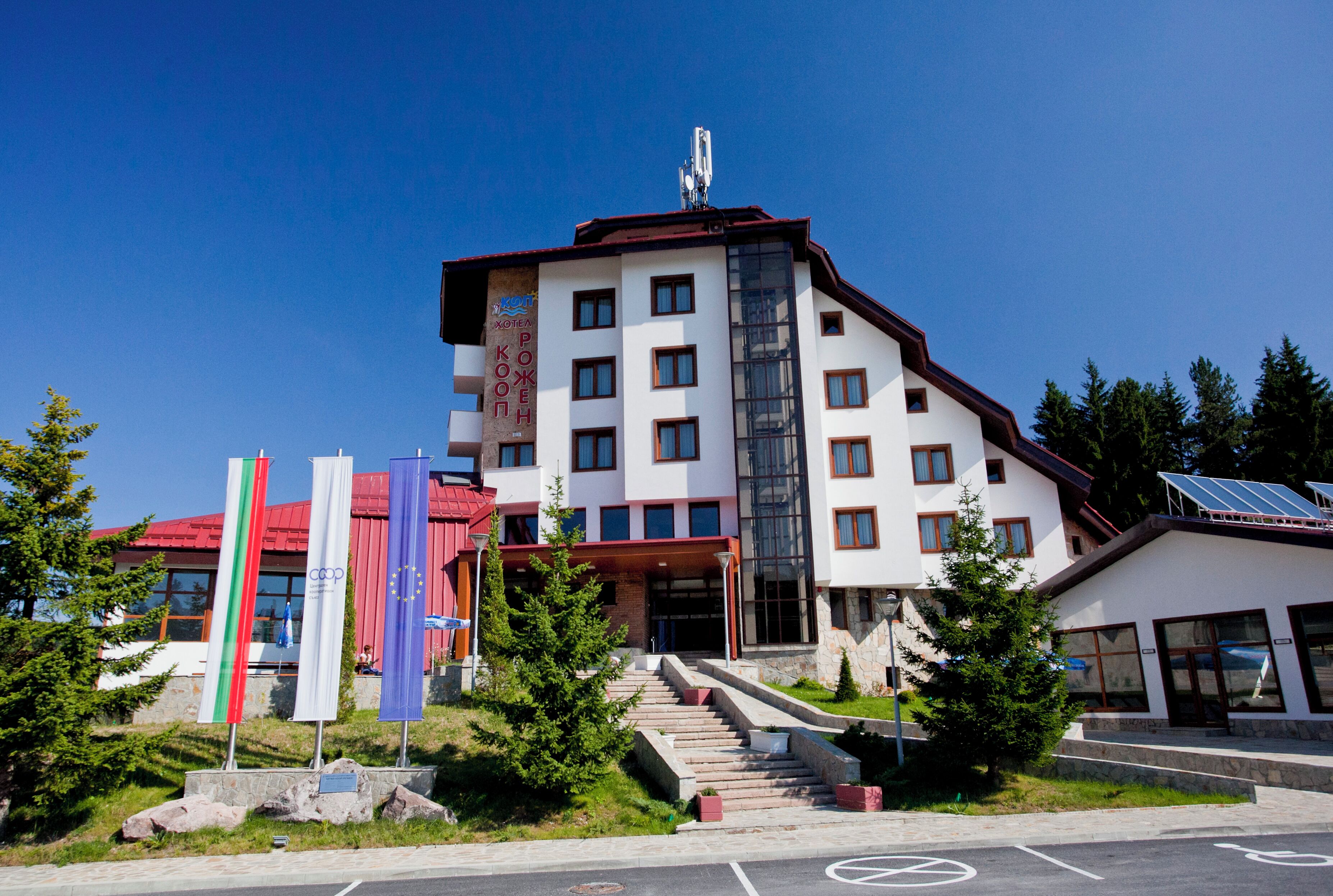 A multi-story hotel with a red roof, multiple windows, and a staircase leading to the entrance.