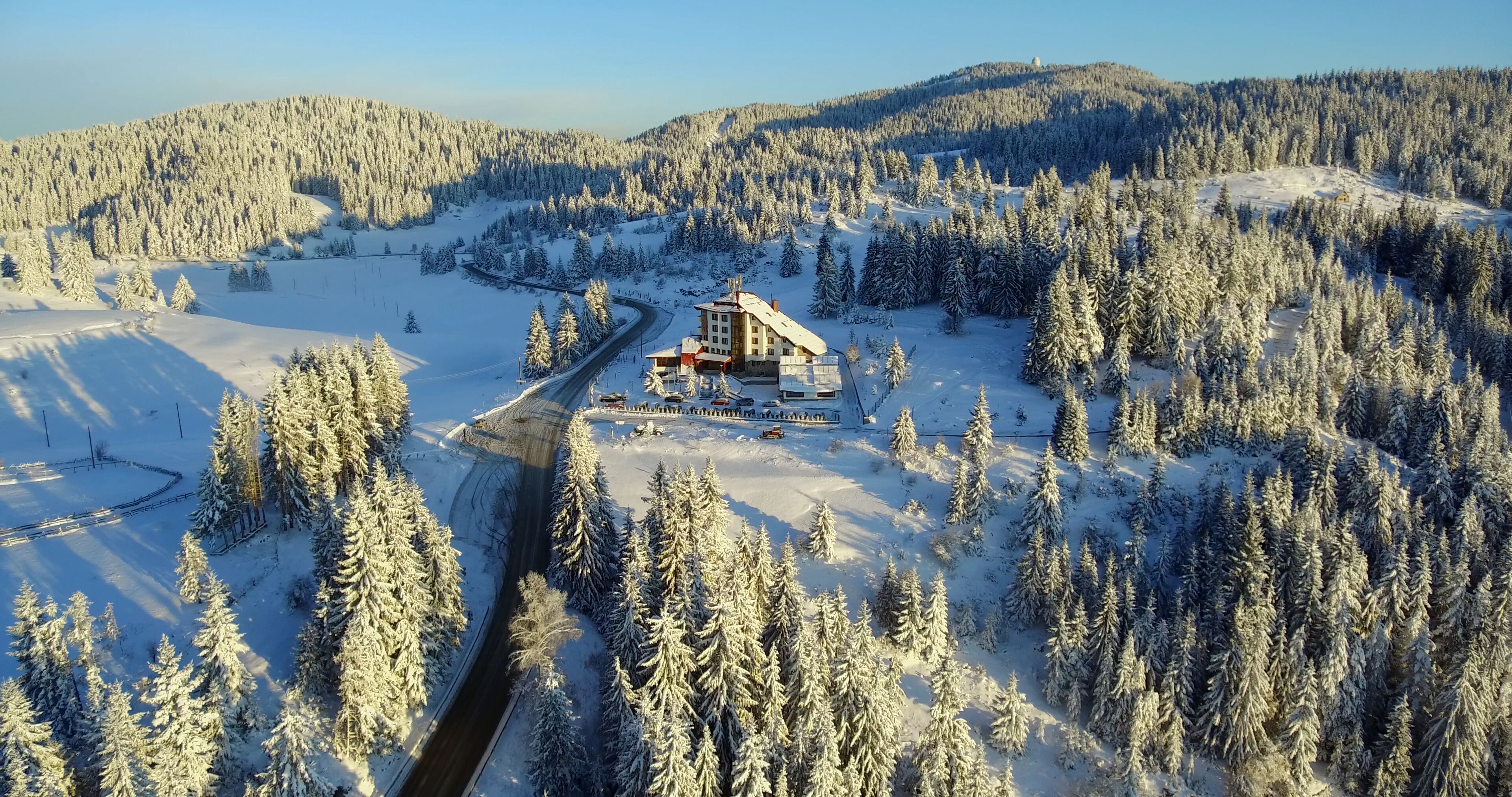A snow-covered landscape with a building surrounded by trees.
