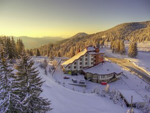 A snow-covered lodge with a ski slope in the background.