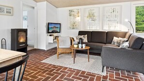 Ein gemütliches Wohnzimmer mit Kamin, einer Couch, einem Fernseher und einem Essbereich.