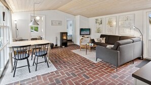 Ein modernes Wohnzimmer mit Kamin, einer Couch, einem Fernseher und einem Essbereich mit Stühlen und einem Tisch.