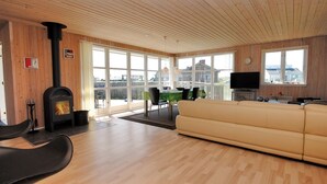 A spacious living room with a fireplace, a sofa, a television, and a dining area with a table and chairs. - "Ernbiorn" -  from the sea by Interhome (Harboøre)