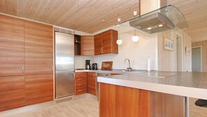 A modern kitchen with wooden cabinets, a stainless steel refrigerator, a built-in oven, a coffee maker, and pendant lighting. - "Ernbiorn" -  from the sea by Interhome (Harboøre)