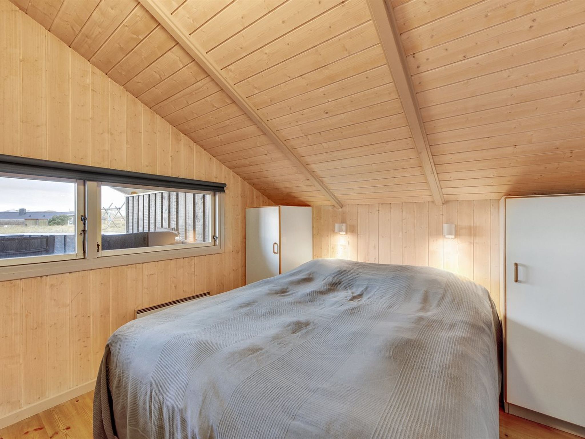 Een slaapkamer met een groot bed, een raam, een kledingkast en een witte kast.