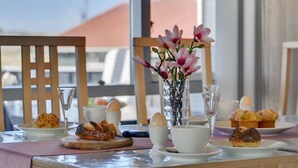 Ein Frühstückstisch mit Gebäck, einer Blumenvase und Blick ins Freie.