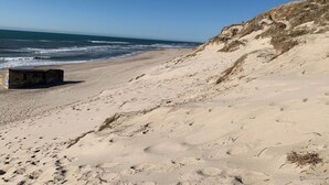Ein sandiger Strand mit Fußabdrücken und einer kleinen Struktur.