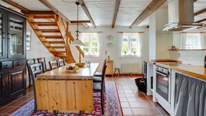 Eine Küche mit Holztisch, Stühlen, einer Treppe und einem Herd.