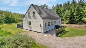 Einbungalow mit geneigtem Dach, einem Schotterweg und einem Holzzaun.