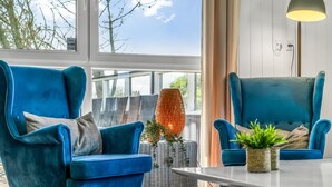Un salon moderne avec deux fauteuils bleus, une table basse en osier et un lampadaire.