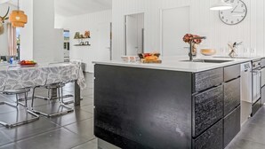 Une cuisine moderne dotée d’un grand îlot central, de meubles blancs et d’une horloge murale.