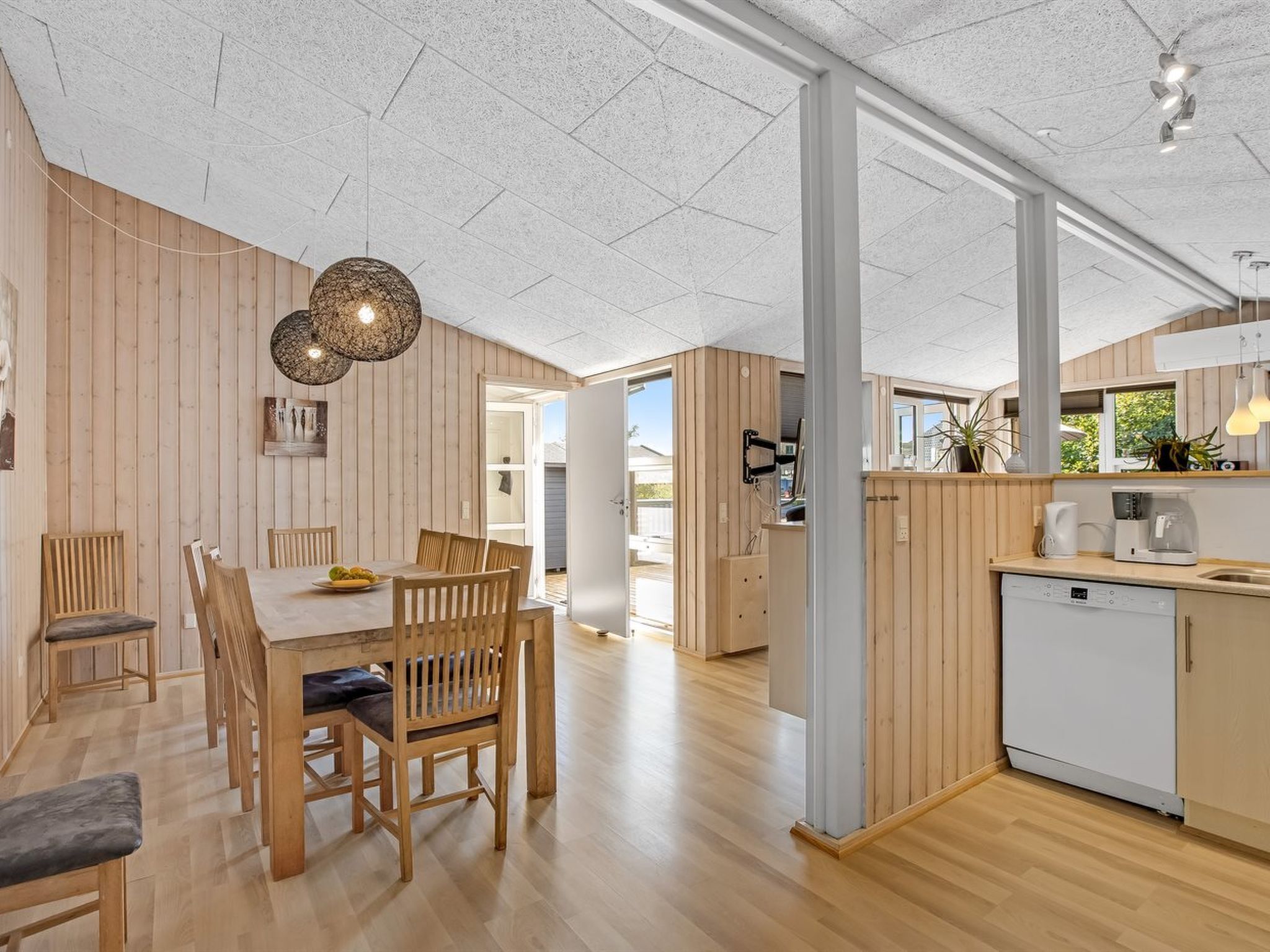 Ett modernt kök med träskåp, diskmaskin och kaffebryggare.