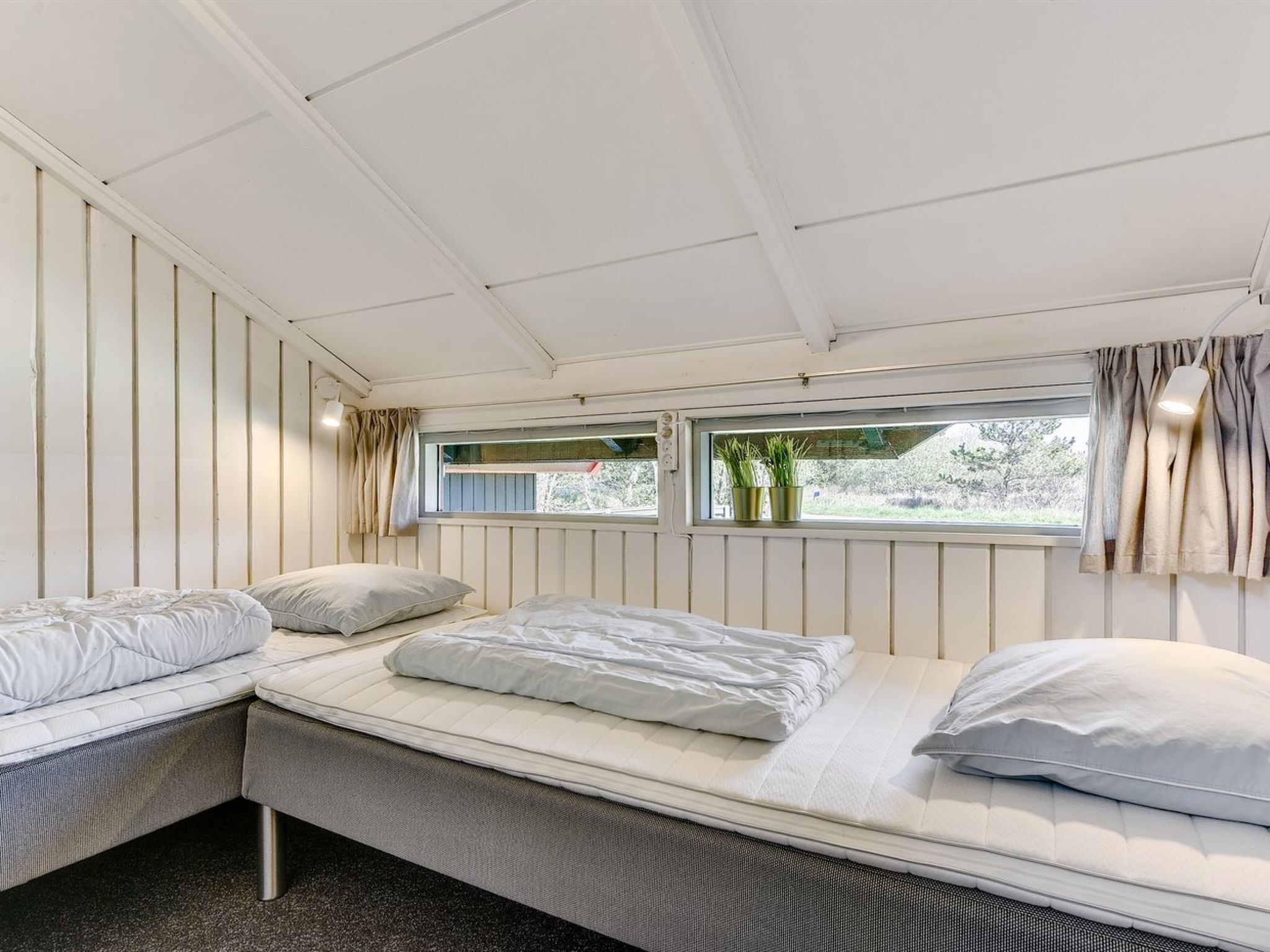 Une chambre avec un lit superposé, une fenêtre avec des rideaux et une vue sur la verdure.