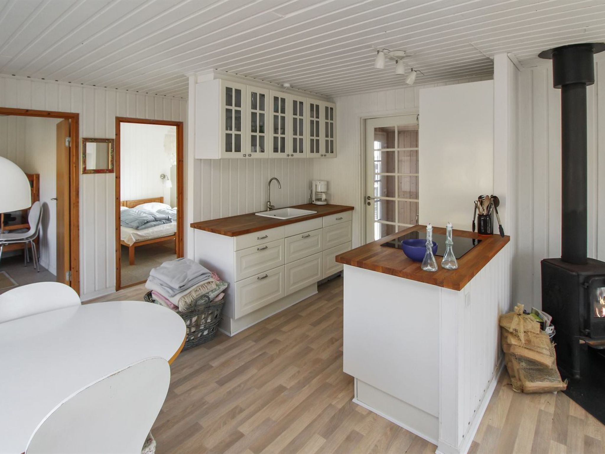 A compact, modern kitchen with white cabinetry, a wooden countertop, and a black stove.