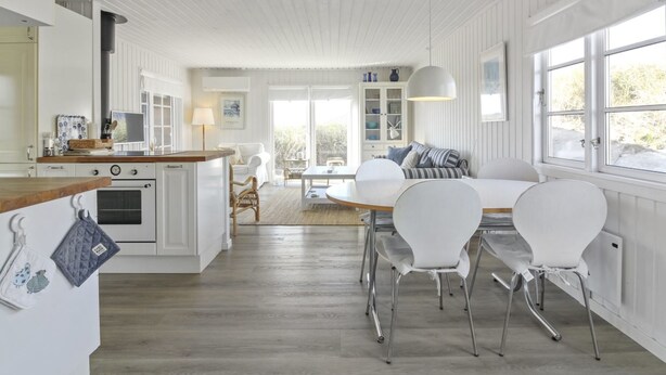 A spacious kitchen with a wooden countertop, a dining area with white chairs and a table, and a living area with a sofa and a large window. - "Adelita" - 100m from the sea by Interhome (Løkken)