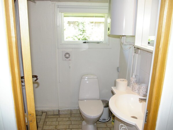 A small, compact bathroom with a toilet, a sink, and a window.