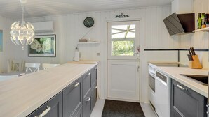 Una cocina moderna con armarios blancos, un reloj, un letrero que dice 'relax' y una lámpara colgante.