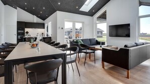 Ein modernes Interieur mit Essbereich, Wohnzimmer mit Sofa und Küche.