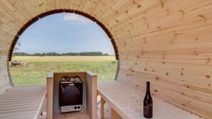 Eine Holzsauna mit einer Bank und einem Tisch mit einer Flasche und Gläsern.