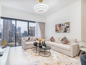A modern living room with a large window, a sofa set, a coffee table, and abstract wall art. - Vogue, Act One near Burj Khalifa and Dubai Mall (Dubai)