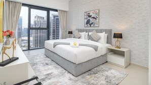 Un dormitorio moderno con una cama grande, una mesita de noche, un escritorio y vistas a la ciudad.