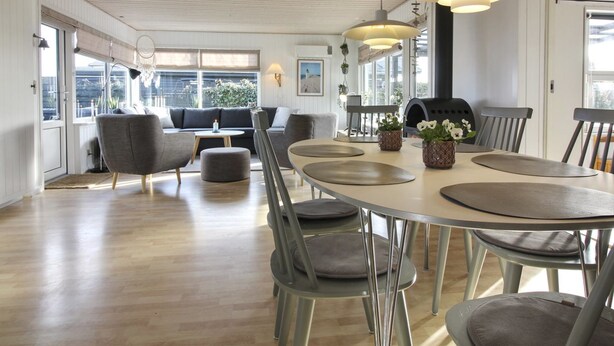 A spacious dining area with a round table, modern chairs, and pendant lighting.