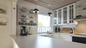 A modern kitchen with white cabinetry, a large island, and pendant lighting.
