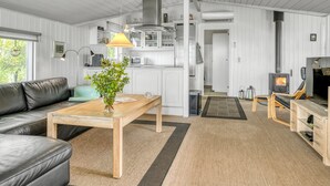 A modern, well-lit living room with a sofa, a wooden coffee table, and a potted plant. - "Eske" - 200m to the fjord by Interhome (Aabybro)