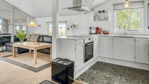 A modern kitchen with white cabinetry, a built-in oven, and a window overlooking greenery. - "Eske" - 200m to the fjord by Interhome (Aabybro)